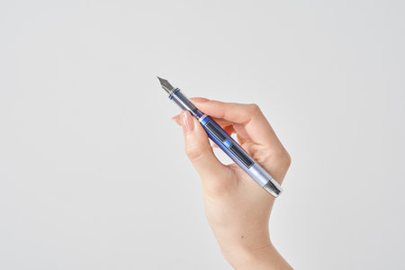 woman's hand holding a fountain pen and white backgroundの写真素材
