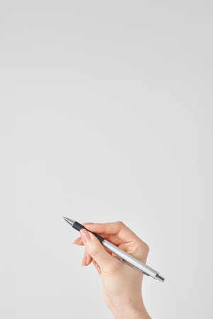 White background with female hand holding black ballpoint penの写真素材