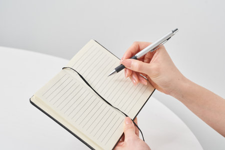 Hand of a woman holding a notepad and white backgroundの写真素材