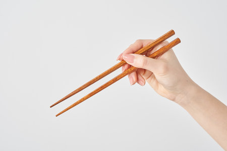 Hand of a woman holding chopsticks and white backgroundの写真素材