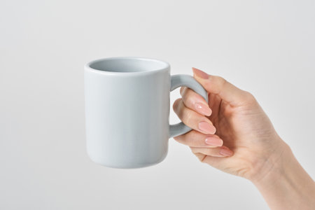 Woman's hand holding a mug and white backgroundの写真素材