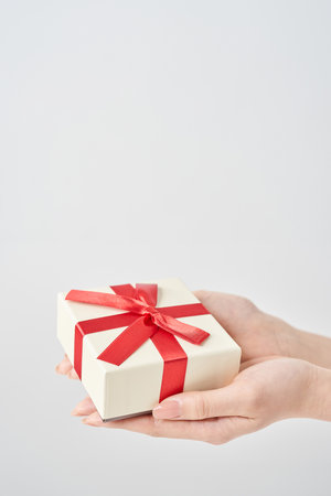 A woman's hand holds a box wrapped for a giftの写真素材