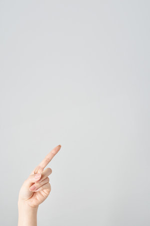 A woman's index finger pointing diagonally upwards and white backgroundの写真素材