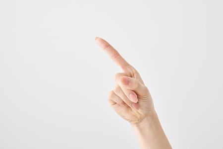 A woman's index finger pointing diagonally upwards and white backgroundの写真素材
