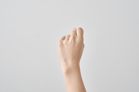 a hand in rock pose of rock-paper-scissors and white backgroundの写真素材