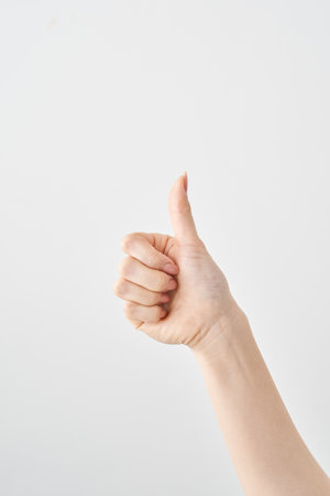 Close-up of hand giving thumbs up and white backgroundの写真素材