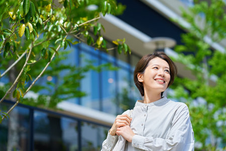 A woman walking down the street with shopping bags on a sunny dayの写真素材