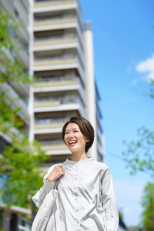 A woman walking down the street with shopping bags on a sunny dayの写真素材