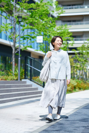 A woman walking down the street with shopping bags on a sunny dayの写真素材