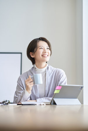 A middle-aged woman taking a break from work with a mugの写真素材