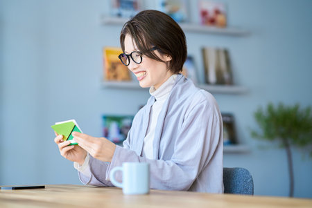 Woman looking at bank account passbook in the roomの写真素材
