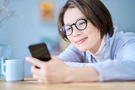 A woman operating a smartphone looking tired in the roomの写真素材