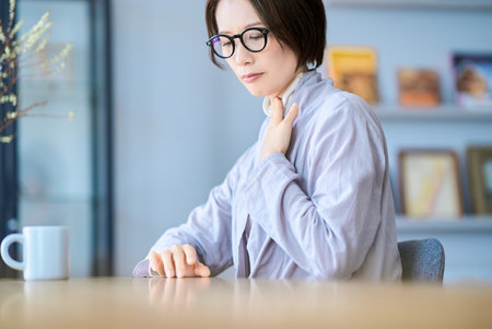 A woman who seems to feel discomfort in her throat in the roomの写真素材