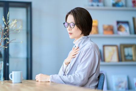 A woman who seems to feel discomfort in her throat in the roomの写真素材