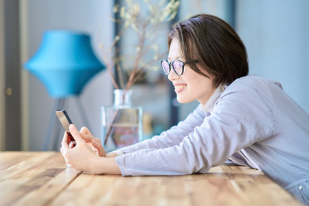 A woman operating a smartphone in the roomの写真素材