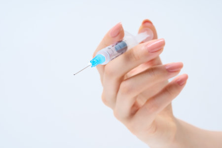 Woman's hand holding a syringe and White backgroundの写真素材