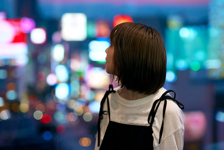 A young woman and a shining downtown at nightの写真素材