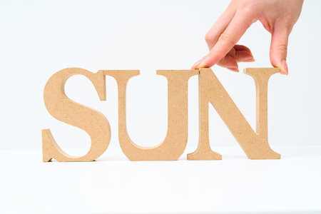 Wooden alphabet blocks arranged with the word "SUN" and white backgroundの写真素材