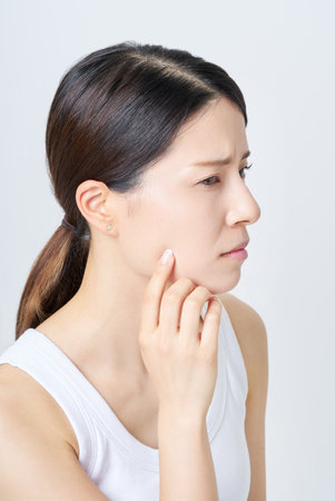 A woman in a tank top suffering from skin problemsの写真素材