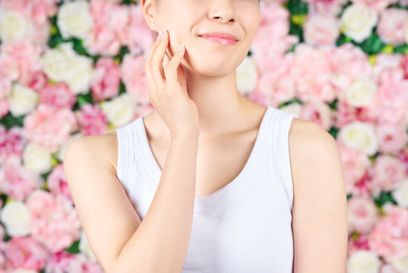 Woman's hands touching her face and flower backgroundの写真素材