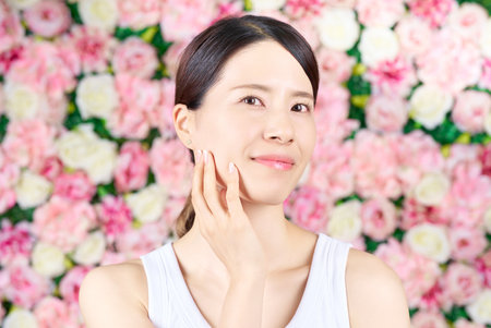 Woman touching her face and flower backgroundの写真素材