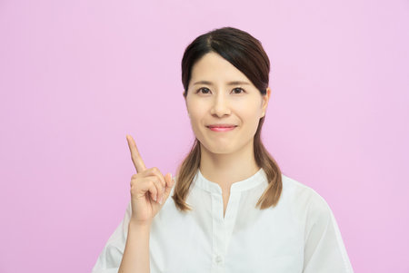 A young woman posing indoors with her index finger raisedの写真素材