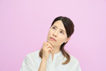 A young woman looking up and thinking indoorsの写真素材
