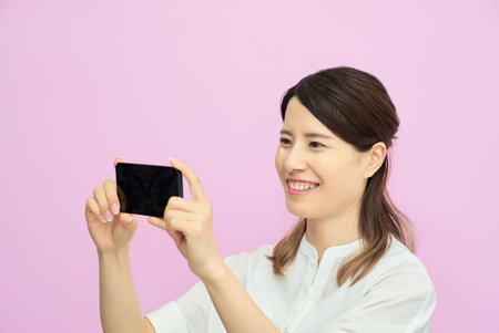Young woman looking at smartphone screen indoorsの写真素材
