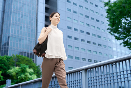 A woman with casual clothes commuting in a business districtの写真素材