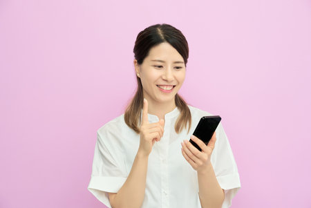 A young woman operating a smartphone indoorsの写真素材