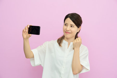 Young woman looking at smartphone screen indoorsの写真素材