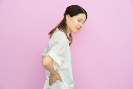 Young woman suffering from back pain indoorsの写真素材