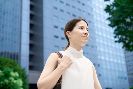 A woman with casual clothes commuting in a business districtの写真素材