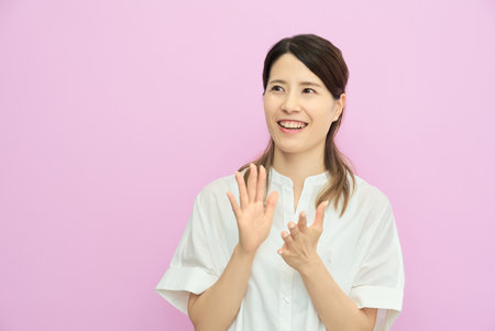 Smiling young woman clapping indoorsの写真素材