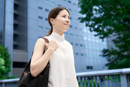 A woman with casual clothes commuting in a business districtの写真素材
