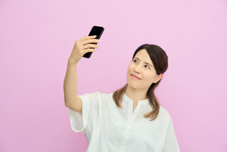 A young woman operating a smartphone indoorsの写真素材