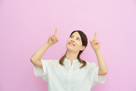 Young woman pointing upwards indoorsの写真素材