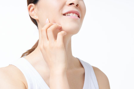 A woman in a tank top checking her skin conditionの写真素材