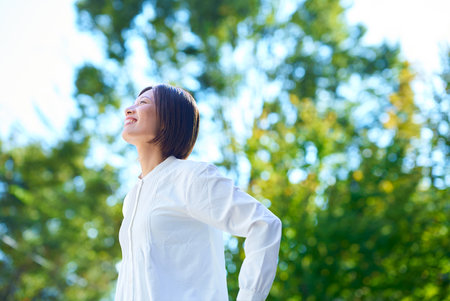 A woman relaxing in the greenery on a sunny dayの写真素材