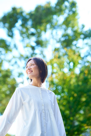 Smiling woman in the greenery on a sunny dayの写真素材