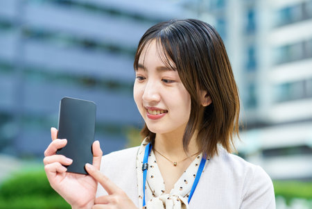 Young business woman holding a smartphone outdoorsの写真素材
