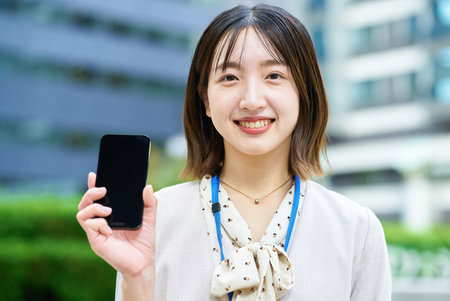 Young business woman holding a smartphone outdoorsの写真素材
