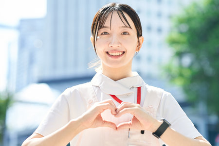 A woman in a white coat posing with a smile outdoorsの写真素材