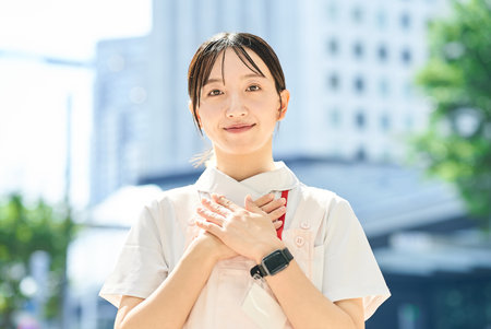 A woman in a white coat posing with a smile outdoorsの写真素材