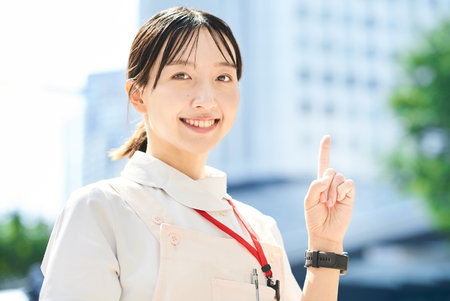 A young woman wearing a white coat and apron outdoorsの写真素材