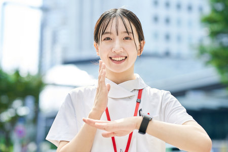 A woman in a white coat signing outdoorsの写真素材