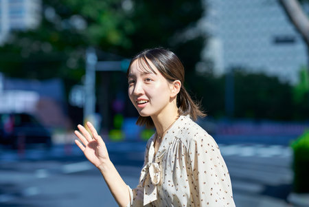 Young woman raising her hand on the streetの写真素材
