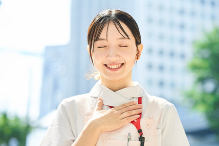 A woman in a white coat posing with a smile outdoorsの写真素材