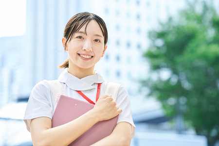 A young woman wearing a white coat and apron outdoorsの写真素材