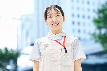 A young woman wearing a white coat and apron outdoorsの写真素材